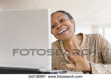 Stock Photo - Mixed race woman using laptop at table. Fotosearch