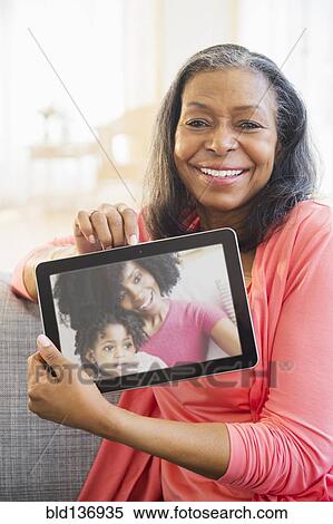 Stock Photography - Mixed race woman using tablet computer on sofa. Fotosearch