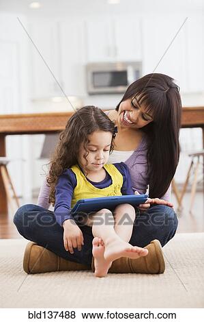Mother and daughter using tablet computer on living room floor View Large Photo Image Stock Photo - Mother and daughter using tablet computer on living room floor. Fotosearch