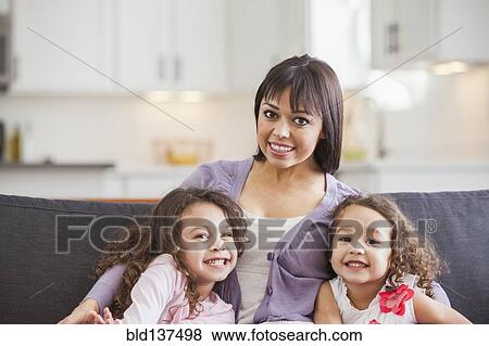 Stock Photo - Mother and daughters smiling on sofa. Fotosearch