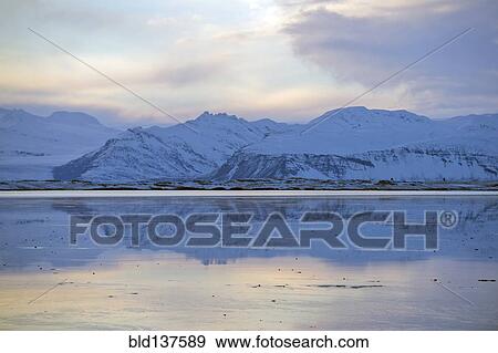 Stock Photo - Mountains reflected in still ocean in arctic landscape. Fotosearch