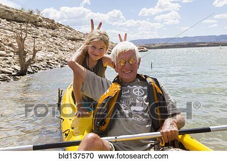 Stock Image - Older Caucasian man posing in kayak with granddaughter. Fotosearch