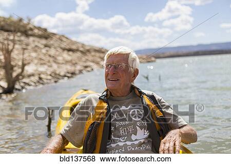 Stock Photo - Older Caucasian man rowing on lake. Fotosearch