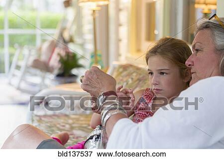 Stock Photo - Older Caucasian woman and granddaughter using cell phone together. Fotosearch