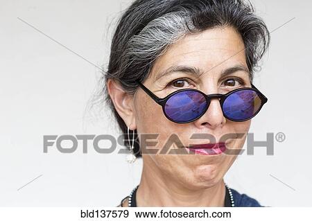 Stock Photo - Older Hispanic woman wearing blue sunglasses. Fotosearch
