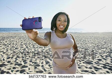 Pregnant woman taking cell phone picture on beach View Large Photo Image Stock Image - Pregnant woman taking cell phone picture on beach. Fotosearch