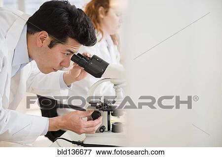 Stock Photo - Scientist using microscope in lab. Fotosearch