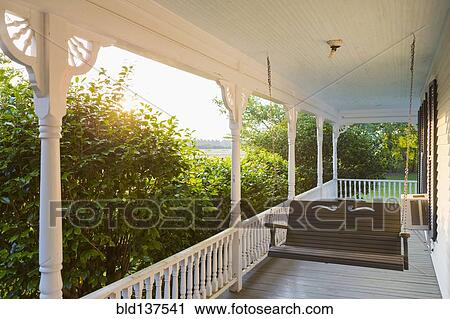 Stock Image - Swing on porch of traditional house. Fotosearch