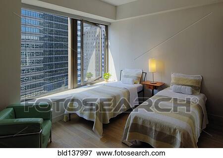 Stock Photo - Twin beds in bedroom overlooking city skyscraper. Fotosearch