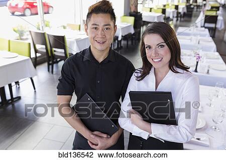 Waiter and waitress smiling together in restaurant View Large Photo Image Stock Image - Waiter and waitress smiling together in restaurant. Fotosearch