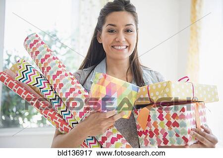 Stock Photo - Woman carrying wrapping paper and gifts. Fotosearch