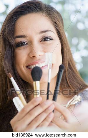 Picture - Woman holding makeup brushes. Fotosearch