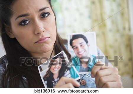 Stock Photograph - Woman holding torn picture of herself with ex-boyfriend. Fotosearch