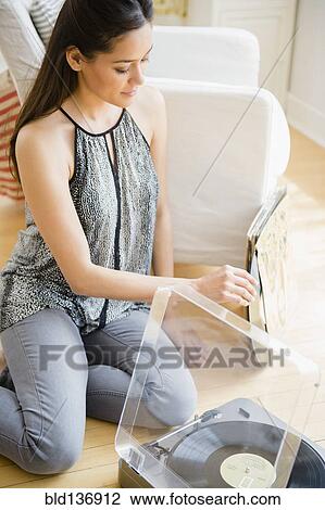 Woman listening to vinyl records in living room View Large Photo Image Stock Image - Woman listening to vinyl records in living room. Fotosearch