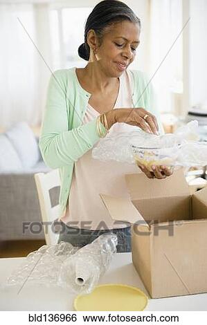 Stock Photograph - Woman packing bowl in cardboard box. Fotosearch