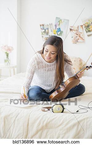 Woman playing violin and taking notes on bed View Large Photo Image Stock Photograph - Woman playing violin and taking notes on bed. Fotosearch