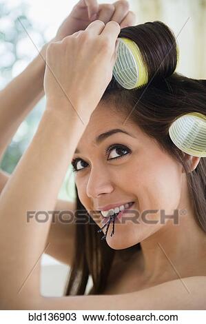 Stock Image - Woman putting her hair up in curlers. Fotosearch