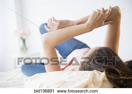 Stock Image - Woman relaxing on bed. Fotosearch