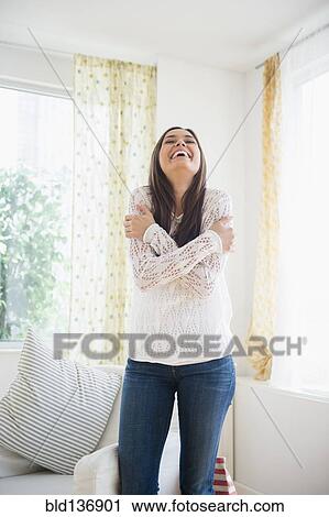 Stock Image - Woman smiling in living room. Fotosearch
