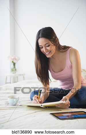 Woman taking notes with tablet computer on bed View Large Photo Image Stock Image - Woman taking notes with tablet computer on bed. Fotosearch
