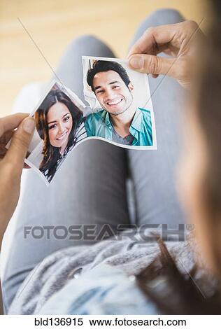 Stock Photography - Woman tearing picture of herself with ex-boyfriend. Fotosearch