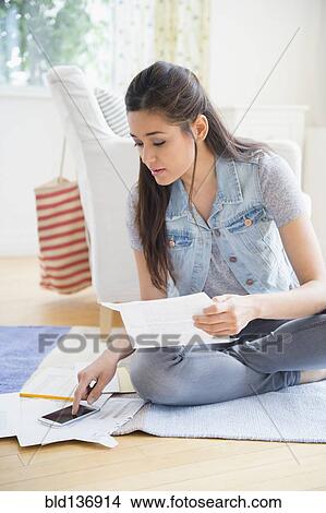 Picture - Woman using cell phone and taking notes. Fotosearch