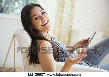 Woman using tablet computer in armchair View Large Photo Image Stock Photo - Woman using tablet computer in armchair. Fotosearch