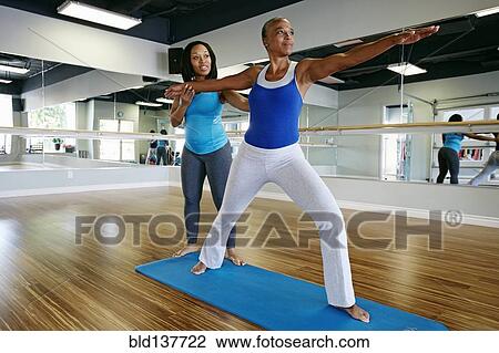 Stock Image - Woman working with yoga teacher in studio. Fotosearch