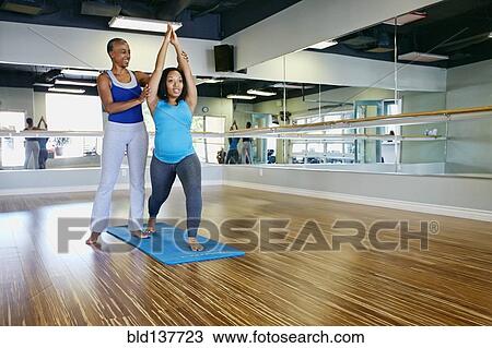 Stock Image - Woman working with yoga teacher in studio. Fotosearch