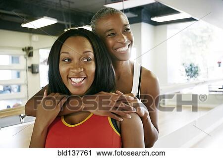 Stock Image - Women hugging in yoga studio. Fotosearch