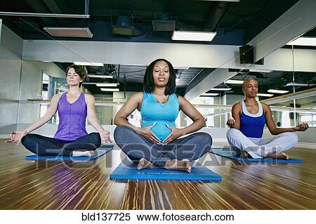 Stock Photography - Women meditating in yoga studio. Fotosearch