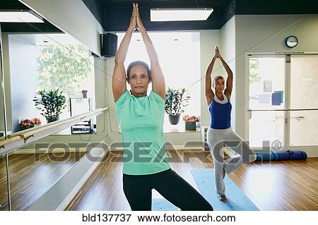 Stock Photo - Women practicing yoga in studio. Fotosearch