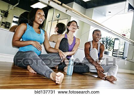 Stock Image - Women relaxing together in yoga studio. Fotosearch