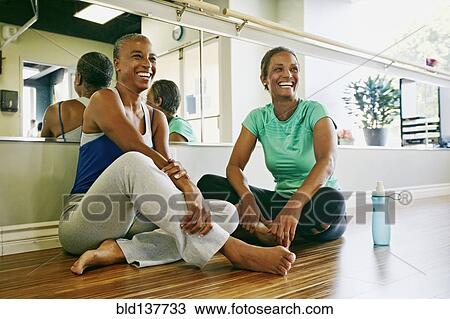 Stock Image - Women relaxing together in yoga studio. Fotosearch