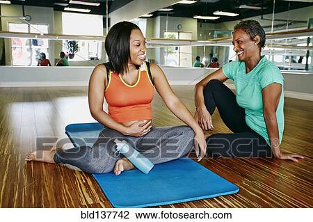 Stock Image - Women talking in yoga studio. Fotosearch