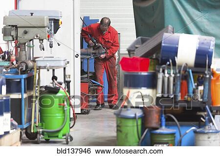Stock Photograph - Worker using machinery in warehouse. Fotosearch