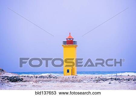 Stock Image - Yellow lighthouse on snowy coastline. Fotosearch