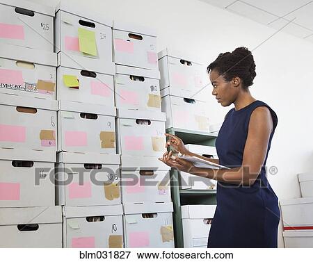 Stock Photo - African American businesswoman searching for files in office. Fotosearch