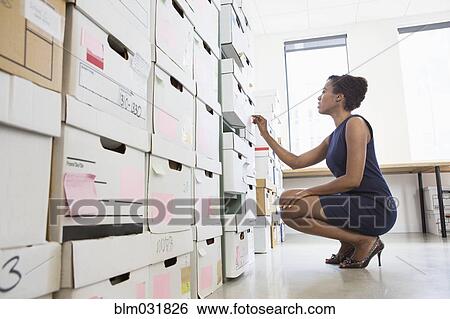 Stock Photograph - African American businesswoman searching for files in office. Fotosearch