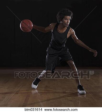 Picture - African American man playing basketball on court. Fotosearch