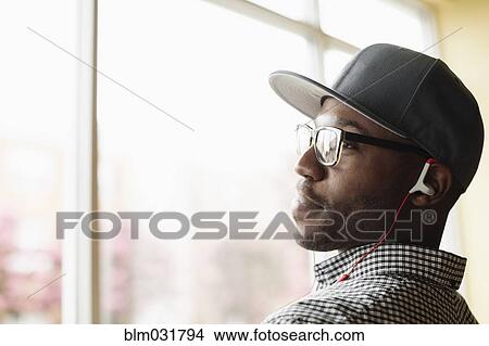 Picture - Black man listening to headphones indoors. Fotosearch