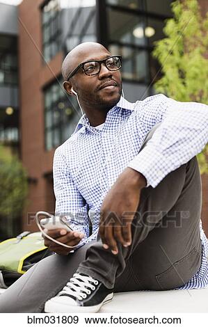 Black man listening to mp3 player in city View Large Photo Image Stock Photo - Black man listening to mp3 player in city. Fotosearch