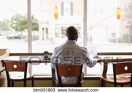 Black man reading paperwork in coffee shop View Large Photo Image Stock Image - Black man reading paperwork in coffee shop. Fotosearch