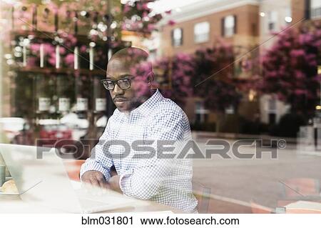 Black man using laptop in coffee shop View Large Photo Image Stock Image - Black man using laptop in coffee shop. Fotosearch