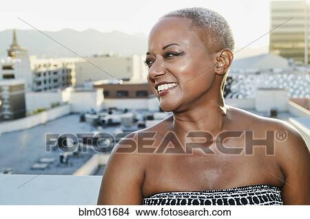 Picture - Black woman smiling on urban rooftop. Fotosearch