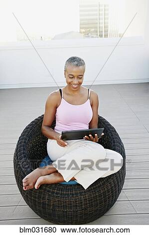 Stock Image - Black woman using digital tablet on urban rooftop. Fotosearch