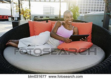 Stock Photo - Black woman using digital tablet on urban rooftop. Fotosearch