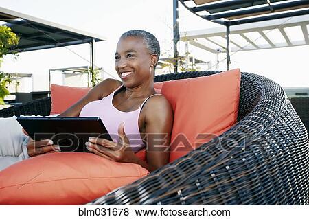 Stock Photo - Black woman using digital tablet on urban rooftop. Fotosearch