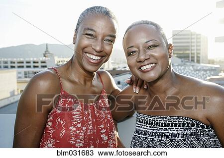 Black women smiling together on urban rooftop View Large Photo Image Stock Image - Black women smiling together on urban rooftop. Fotosearch