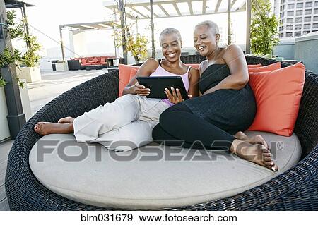 Stock Photo - Black women using digital tablet together on urban rooftop. Fotosearch